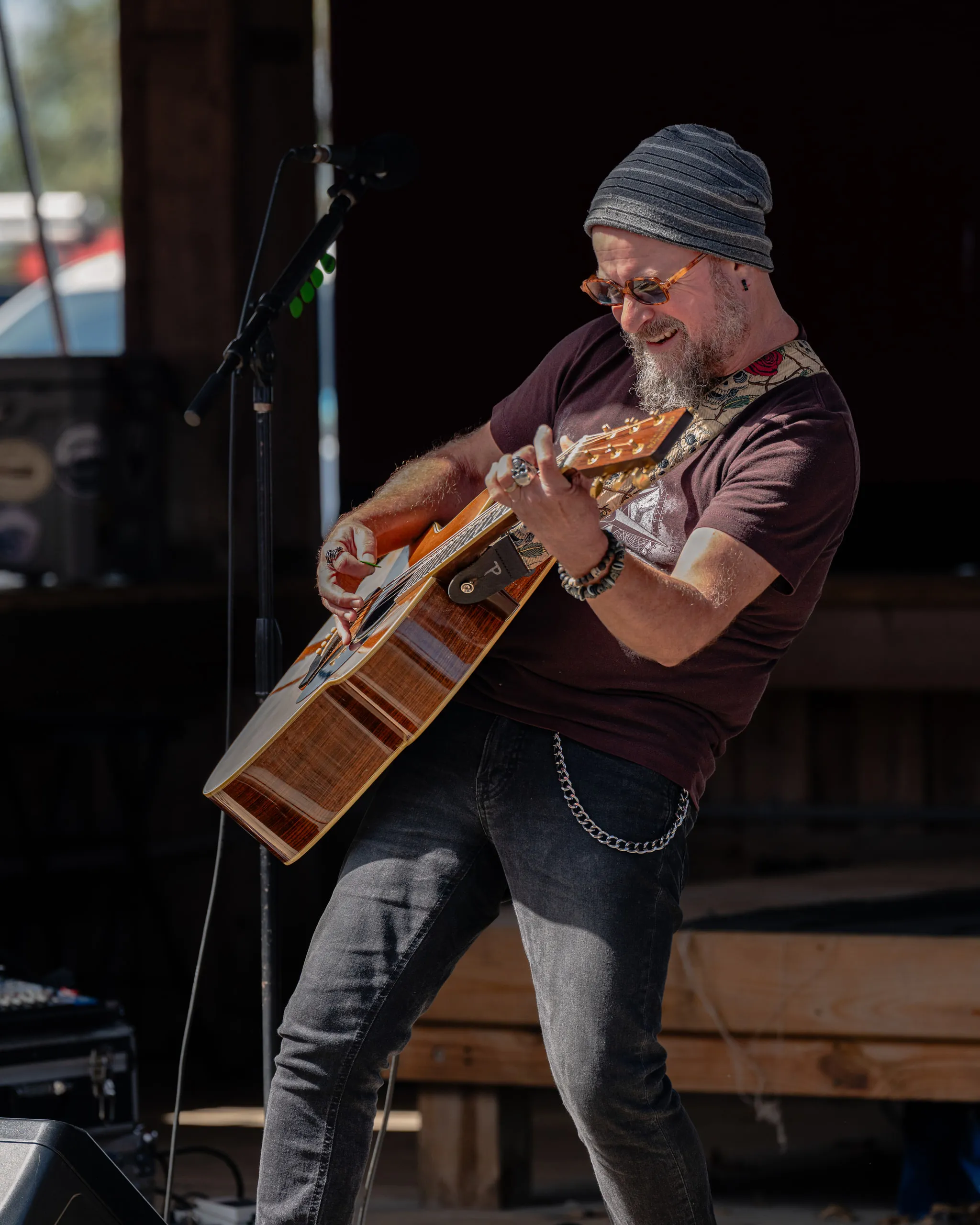 Close in on the guitarist and the body of the acoustic as a chord lands